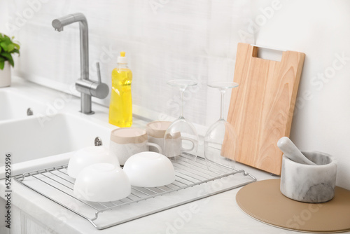 Drying rack with clean dishes near sink in stylish kitchen