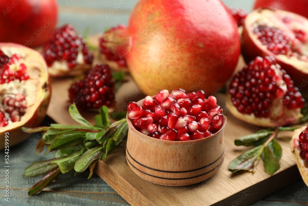 Delicious ripe pomegranate kernels in bowl on wooden board, closeup Delicious ripe pomegranate kernels in bowl on wooden board, closeup
