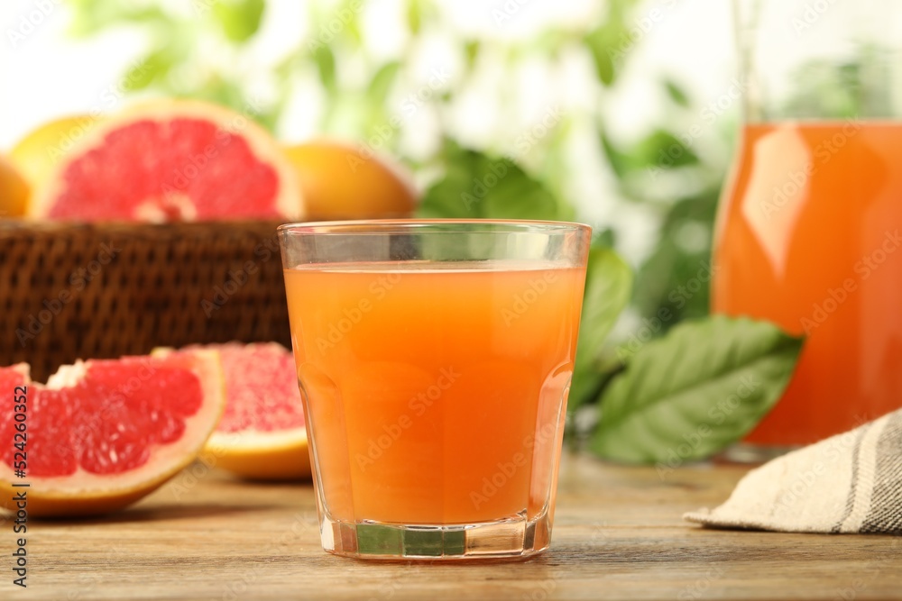 Glass of delicious grapefruit juice on wooden table against blurred background Glass of delicious grapefruit juice on wooden table against blurred background