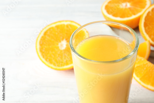 Glass of orange juice and fresh fruits on white wooden table, closeup