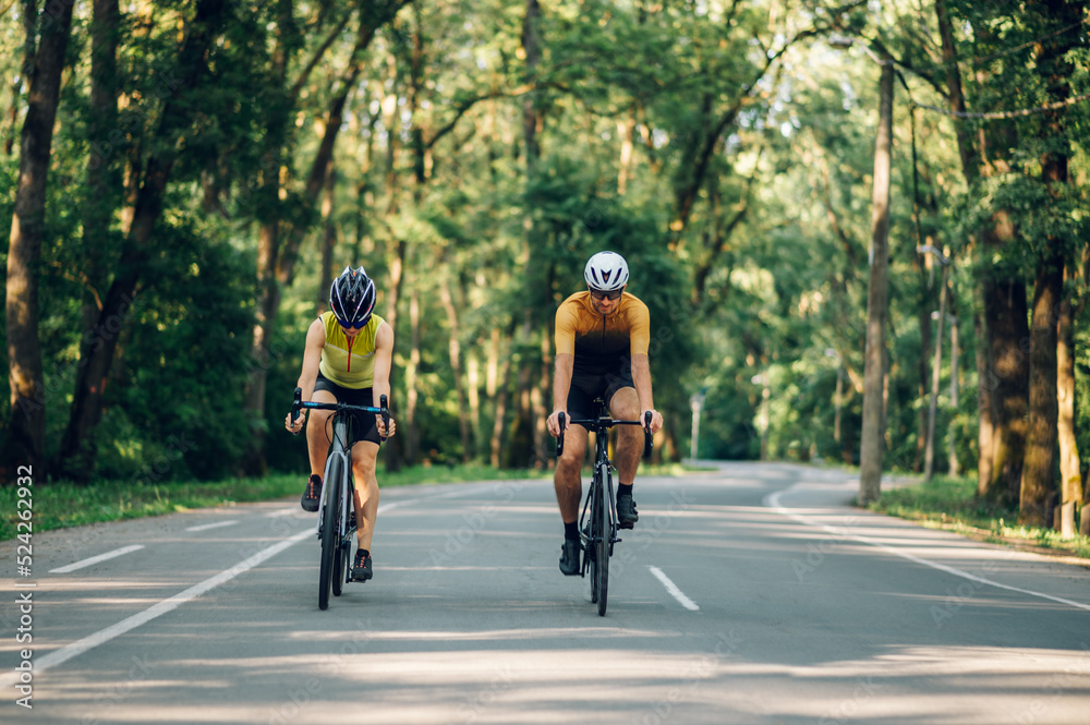 Couple riding road bicycles outside and wearing helmets and sunglasses