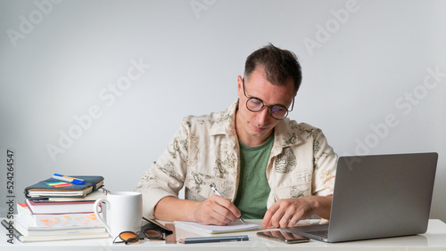 A student at a table with textbooks and notebooks writes in a notebook