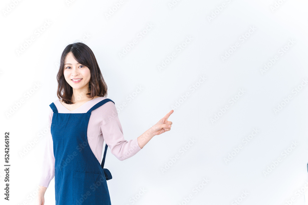 エプロンを着ておすすめを示す若い女性 エプロンを着ておすすめを示す若い女性