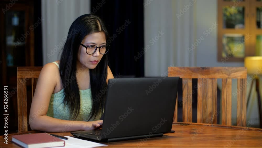 Female professional wearing eyeglasses working on laptop typing on