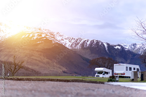 Caravan/motorhome against a wild backdrop of snow-capped mountains, with atmospheric glow effect 