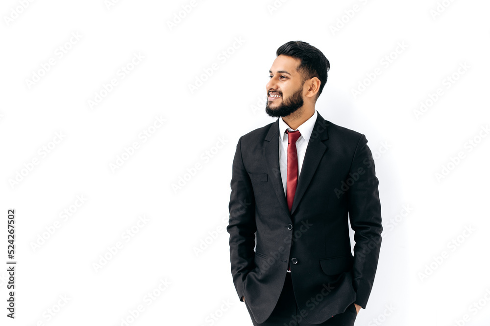 Handsome elegant influential arabian or indian man in formal suit, standing on isolated white background, looking to the side, thinking, planning, dreaming, smiling. Copy-space for your presentation Handsome elegant influential arabian or indian man in formal suit, standing on isolated white background, looking to the side, thinking, planning, dreaming, smiling. Copy-space for your presentation