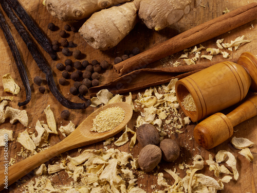 An assortment of spices, ginger; allspice; vanilla bean; cinnamon stick; dried ginger; nutmeg, with a mortar and pestle