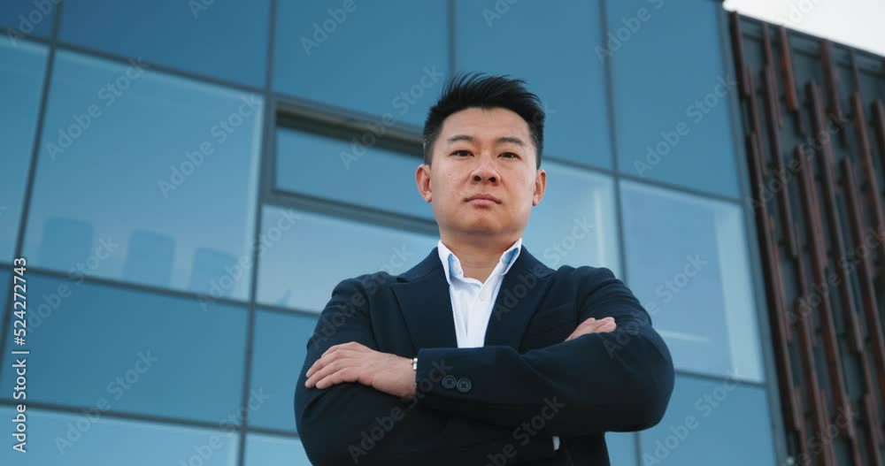 Portrait of a successful businessman, with arms, crossed standing near a office building
