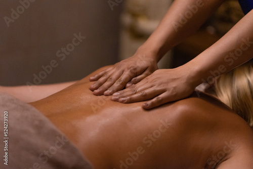 A masseur doing a hand and arm massage to adult woman in her back. Massage treatment in spa salon.