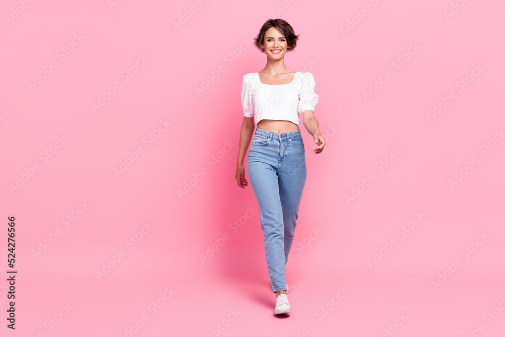 Full length photo of adorable pretty girl dressed white blouse walking empty space isolated pink color background