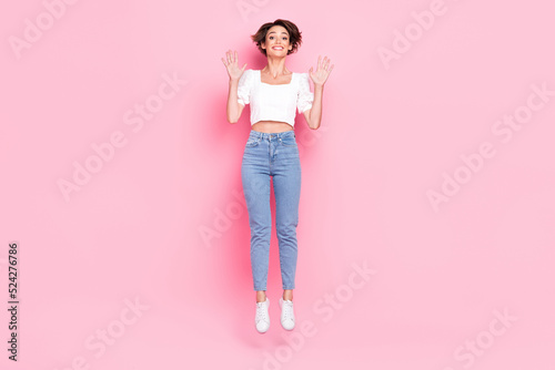 Full length photo of pretty excited girl dressed white blouse smiling jumping up isolated pink color background