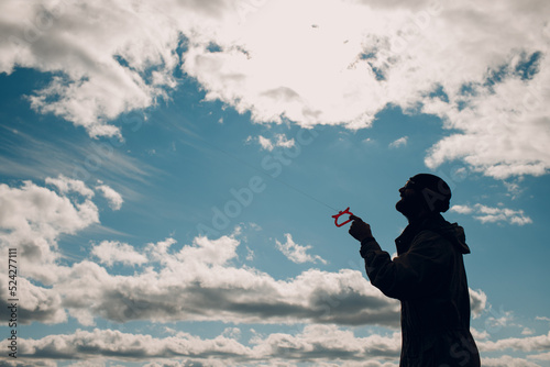 Young man flying a kite against blue sky.