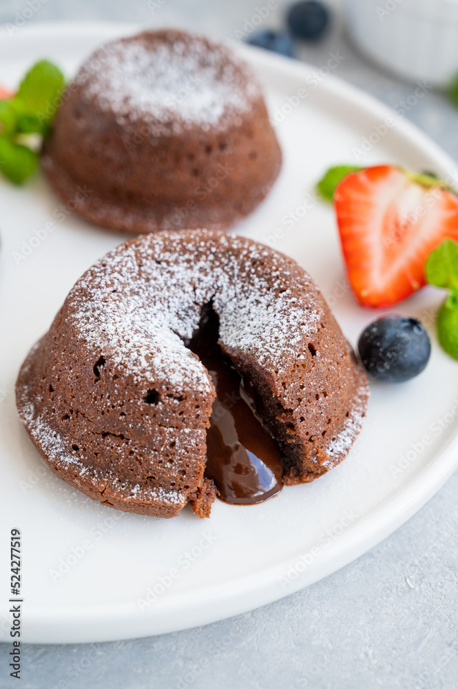 Chocolate fondant lava cake with fresh berries on a plate on a gray background. Chocolate fondant lava cake with fresh berries on a plate on a gray background.