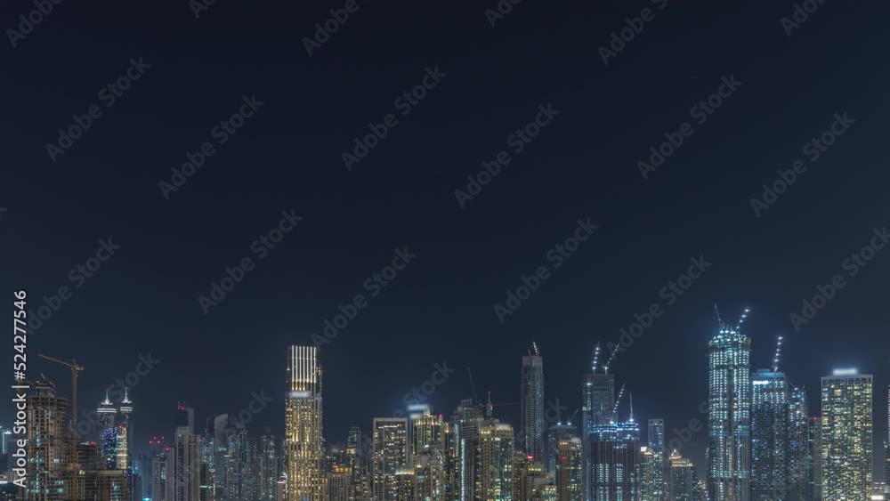 Panorama showing Dubai Downtown and business bay night timelapse with tallest skyscraper and other illuminated towers view from the top in Dubai, United Arab Emirates.