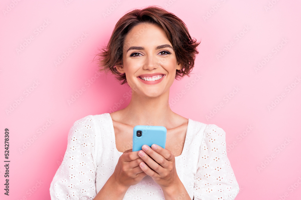 Photo portrait of stunning young woman hold device chatting use social media dressed trendy white garment isolated on pink color background Photo portrait of stunning young woman hold device chatting use social media dressed trendy white garment isolated on pink color background