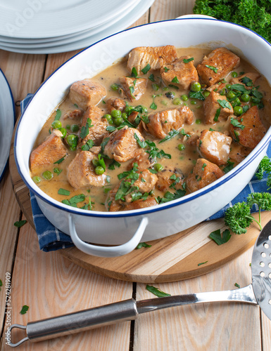 Poultry goulash with cream sauce and green peas in a pot