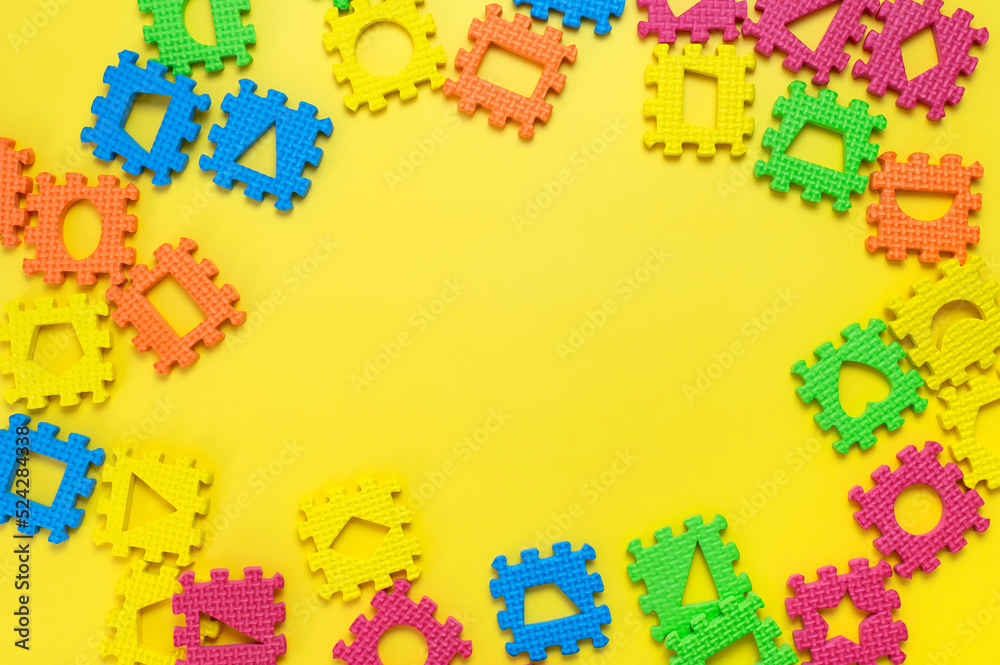 Frame from Soft children's multi-colored jigsaw puzzles with various figures inside on yellow background flat lay. Children's creativity games, development of thinking, education. Abstract background