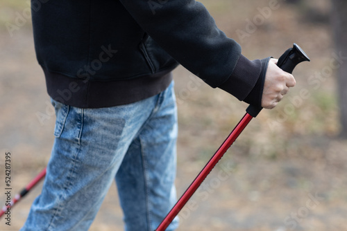 Young man walks with Scandinavian nordic walking sticks. Healthy lifestyle