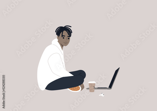 Quadro su tela A young male African character sitting on the floor and working on their laptop