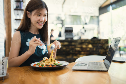 Asian beauty businesswoman start up entrepreneur smile while eating spaghetti happy work job freelance in cafe with laptop and mobile phone internet comunication social media marketing