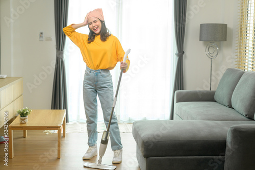 Young happy woman mopping and vacuum the floor in living room.