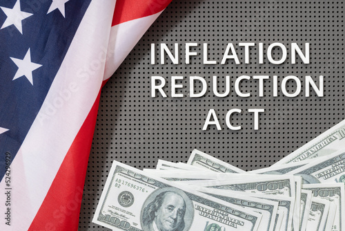 Inflation reduction Act law concept. Fat lay of text, american flag and dollar banknotes photo