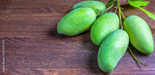 Fresh green mango and green leaf in the basket ,Group of raw mangoes organic on brown wooden backgroundv photo