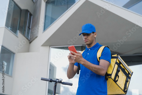 Delivery man doing fast food delivery service with electric scooter - Focus on hand holding mobile phone