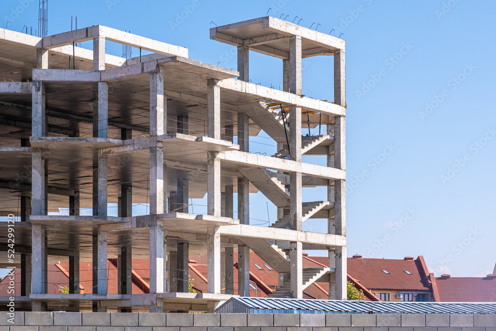 Construction of a multi-storey building. Concrete floors are clearly visible. Stairs, boxes of future apartments