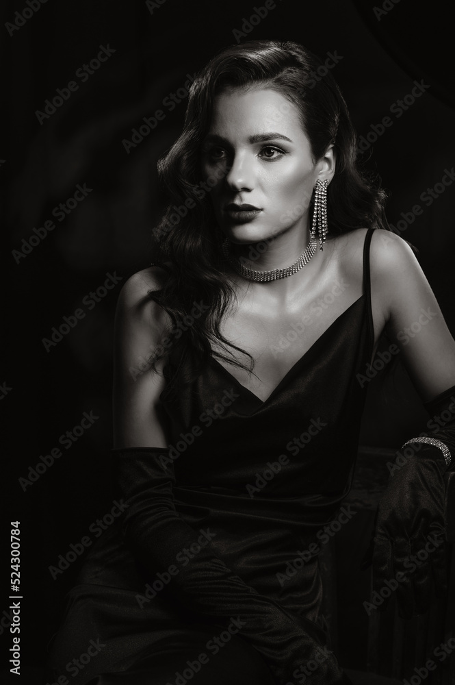 Naklejka premium Portrait of woman in classic retro style of black and white Hollywood movies. Girl in vintage look with makeup and hairstyle with jewelry and gloves on hands