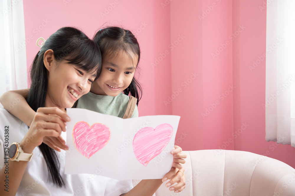 Happy mother's day! Asian child daughter congratulates mom and gives her postcard. Memory greeting card for mom Happy mother's day! Asian child daughter congratulates mom and gives her postcard. Memory greeting card for mom