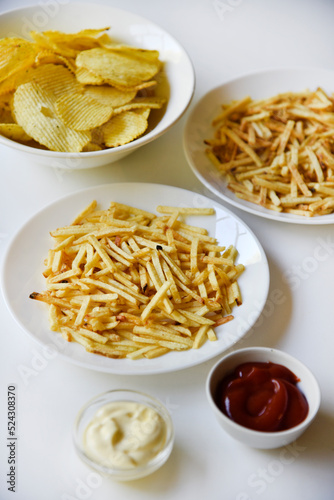 Delicious potato chips straws on a white saucer with sauce. Fast food with fried potato sauce straws.