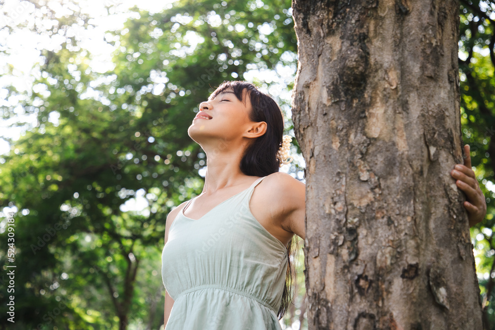 Portrait photo of happy Asian caucasian woman relaxing and breathing fresh air with sunlight in outdoors park. Dreaming and happiness concept Portrait photo of happy Asian caucasian woman relaxing and breathing fresh air with sunlight in outdoors park. Dreaming and happiness concept