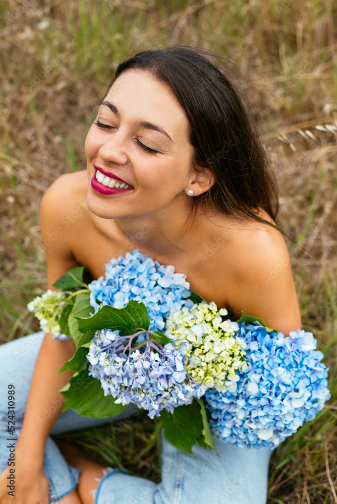 Happy alluring lady with bunch of gentle hortensia flowers in park Happy alluring lady with bunch of gentle hortensia flowers in park