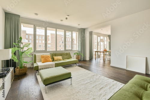 Table with chairs and flowers located near lounge area and kitchen in spacious room of contemporary apartment