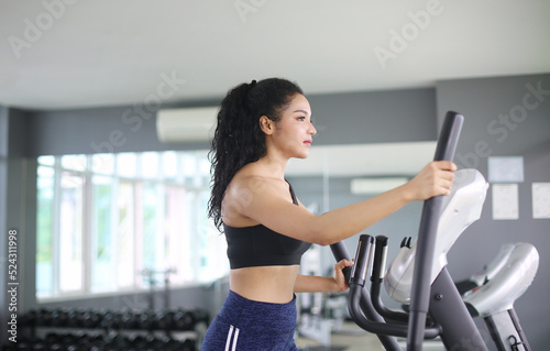 close-up shot of woman working out on elliptical machine at gym