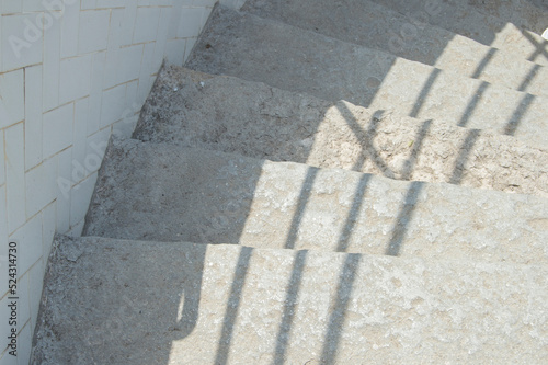Stairs going down with the shadow of a railing