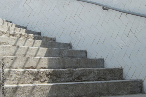 staircase with stone steps next to a tiled wall with iron railing
