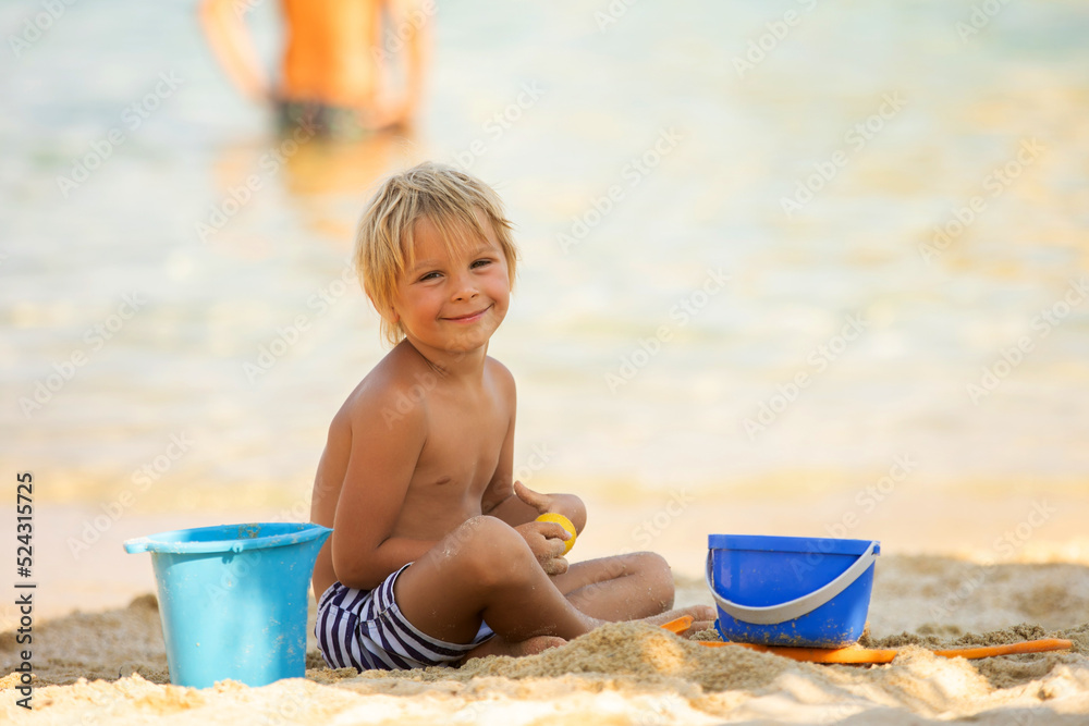 Happy child on the beach, playing in the sand, enjoying summer Happy child on the beach, playing in the sand, enjoying summer