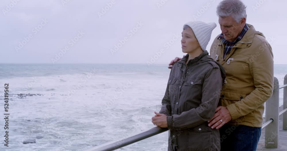 Senior couple hugging in comfort embrace, with care and support, overcoming the grief of cancer or memory loss standing at the oceanside. Elderly husband consoling senile wife over dementia disease Senior couple hugging in comfort embrace, with care and support, overcoming the grief of cancer or memory loss standing at the oceanside. Elderly husband consoling senile wife over dementia disease