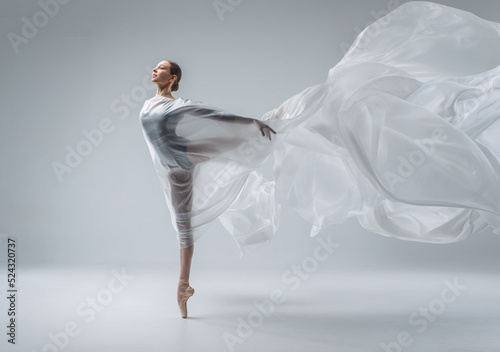 Fototapeta Naklejka Na Ścianę i Meble -  Ballerina in dark ballet leotard dancing on ballet pointe shoes in white studio 