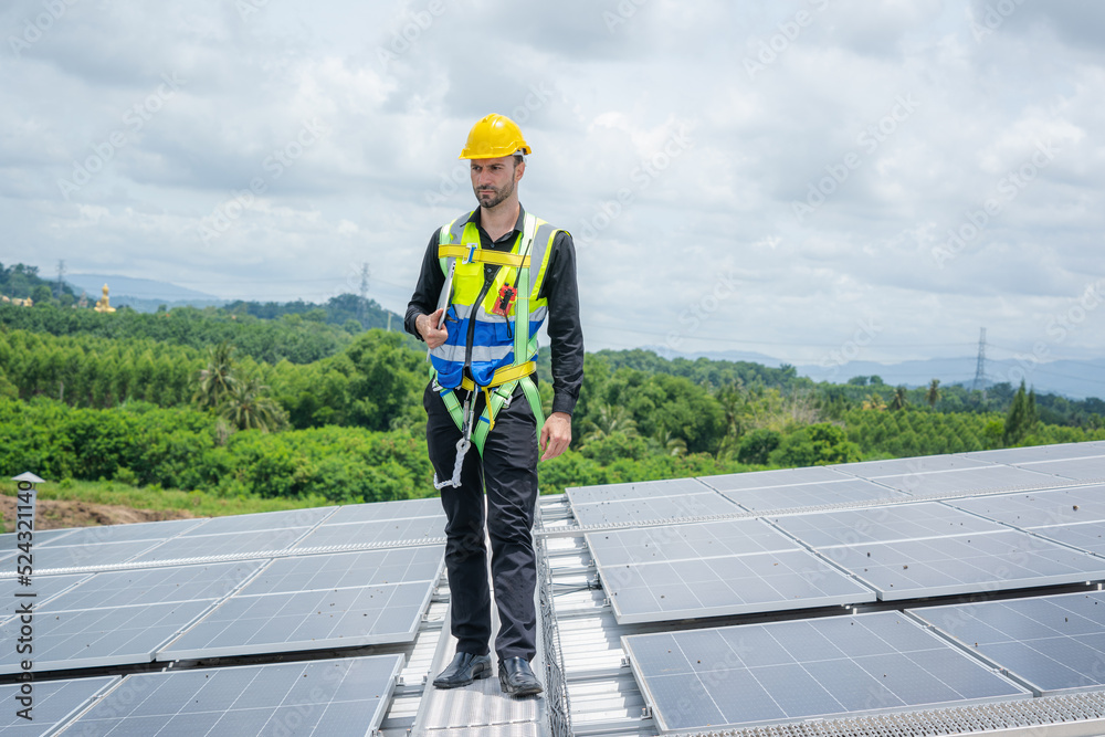 Engineer working and maintenance with solar batteries near solar panels at sunny day on roof structure of building factory,Alternative energy to conserve the world's energy.