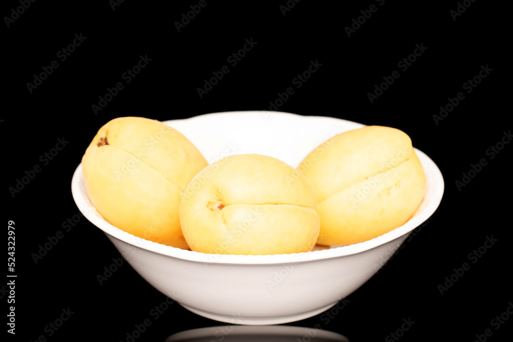 Three bright yellow juicy pineapple apricots in a pottery, macro, isolated on a black background. Three bright yellow juicy pineapple apricots in a pottery, macro, isolated on a black background.