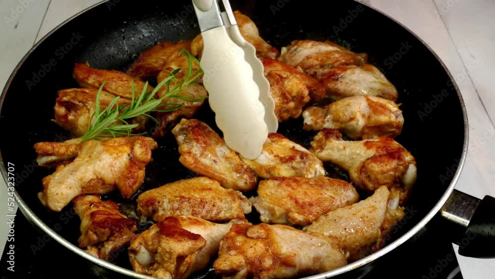 Many sprinkled with spices sliced chicken wings, preparation and turning in hot frying pan. Many sprinkled with spices sliced chicken wings, preparation and turning in hot frying pan.