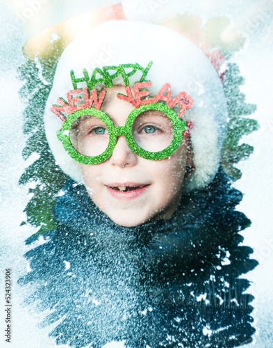 Fototapeta Naklejka Na Ścianę i Meble -  boy in santa claus costume looking throught the snowy window, happy new year concept