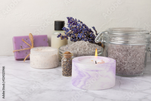 Lavender spa.Sea salt,lavender flowers,aroma candle,body cream and handmade soap.Natural herbal cosmetics with lavender flowers on marble background.Relax concept.Beauty treatments.Copy space.