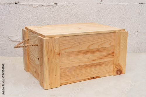 Wooden box made of planks with a rope handle for storing and transporting objects on a textured light background