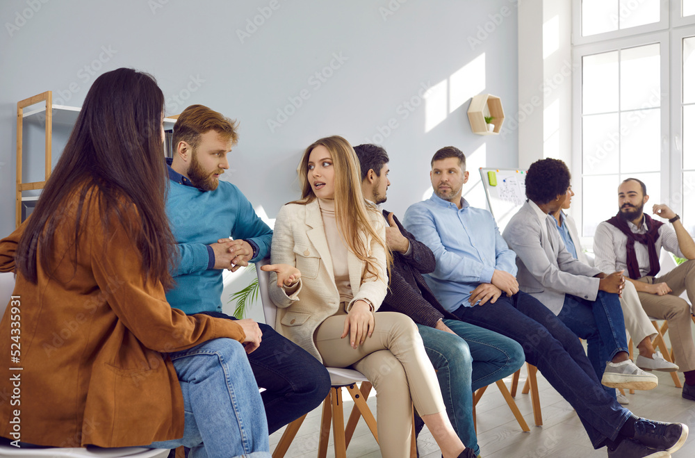 Group of serious business people talking during meeting in office. Team of entrepreneurs or corporate managers sitting in row, discussing various topics, providing arguments and exchanging opinions Group of serious business people talking during meeting in office. Team of entrepreneurs or corporate managers sitting in row, discussing various topics, providing arguments and exchanging opinions