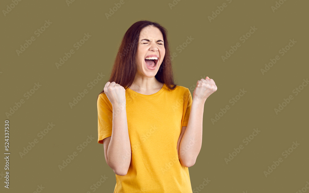 Lucky young woman achieves her goal, wins lots of money or inherits huge fortune. Happy excited crazy girl in T shirt isolated on solid brown background fist pumping and screaming YES I DID IT, HURRAY Lucky young woman achieves her goal, wins lots of money or inherits huge fortune. Happy excited crazy girl in T shirt isolated on solid brown background fist pumping and screaming YES I DID IT, HURRAY