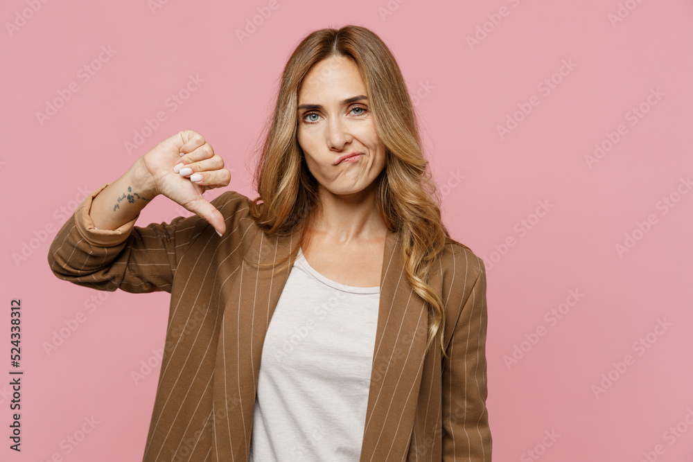 Young displeased disappointed sad employee business woman 30s she wearing casual brown classic jacket showing thumb down dislike gesture isolated on plain pastel light pink background studio portrait. - obrazy, fototapety, plakaty 